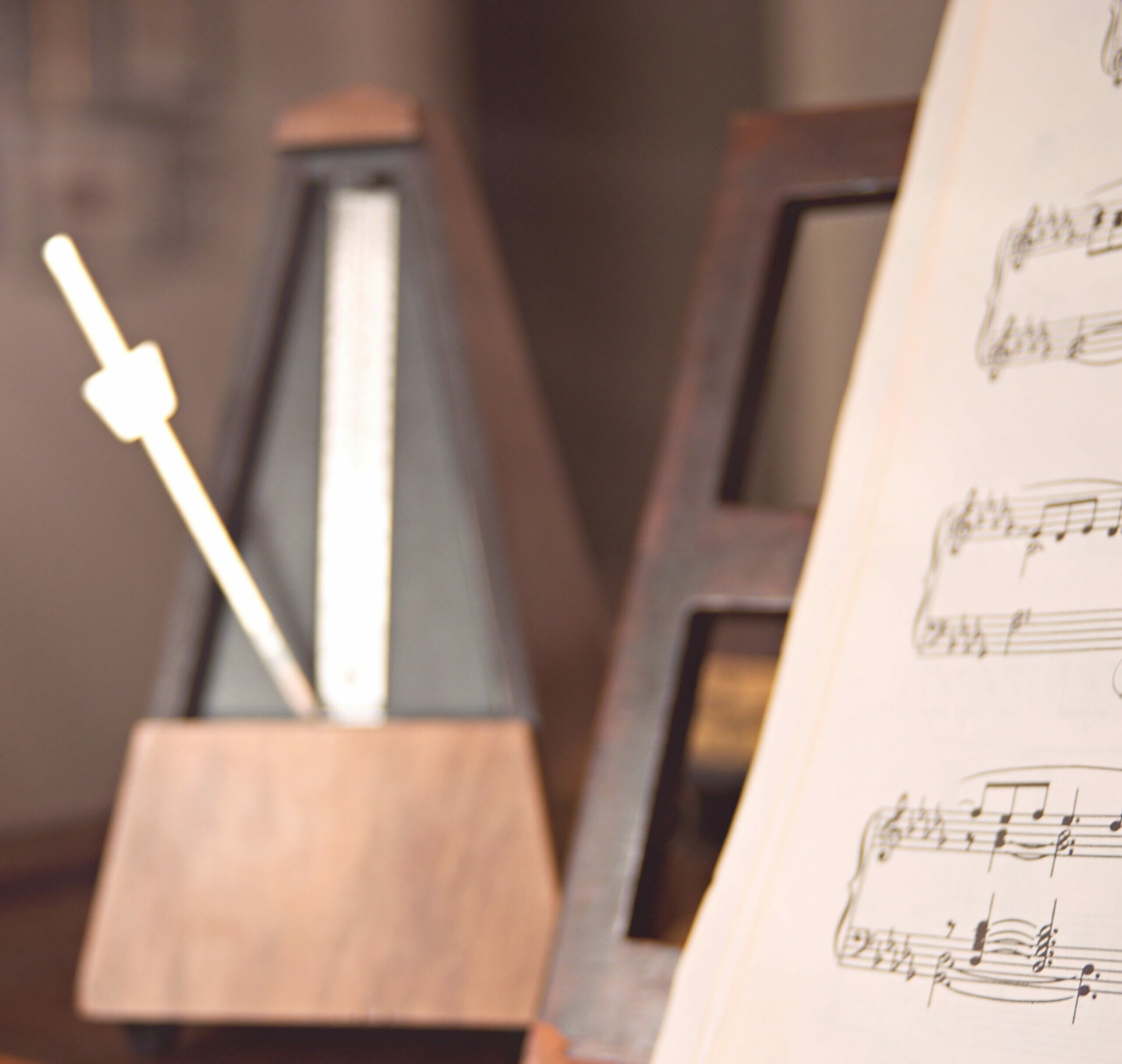 SFS-symphony-feng-shui-paris Partition de musique devant un métronome en bois foncé. Venez découvrir l'histoire de Symphonie Feng Shui