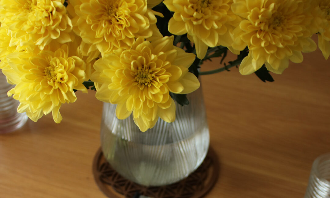 Rapport d'aménagement intérieur feng shui - axes d'amélioration - Symphonie Feng-Shui, sur une table en bois avec un vase et des fleurs jaunes -Feng Shui Audit Aménagement intérieur Paris.