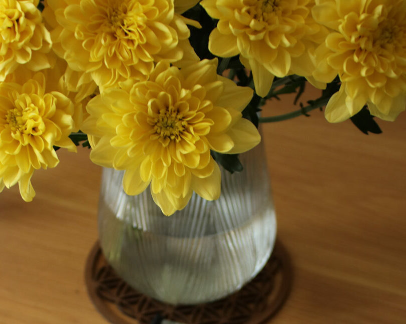 Rapport d'aménagement intérieur feng shui - axes d'amélioration - Symphonie Feng-Shui, sur une table en bois avec un vase et des fleurs jaunes -Feng Shui Audit Aménagement intérieur Paris.